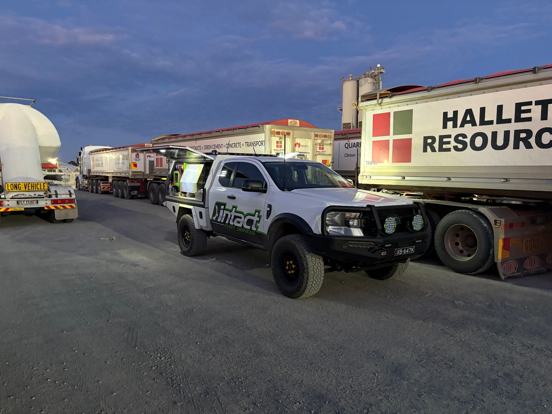 Intact Fleet Services ute alongside heavy transport trucks at dusk